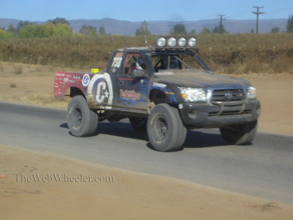 Black Toyota Tacoma off-road race truck numbered 735 on a paved desert road