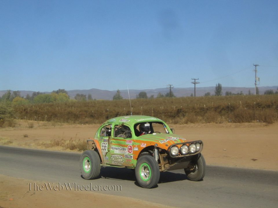 Green and orange VW Beetle-based off-road race buggy on dirt-lined road