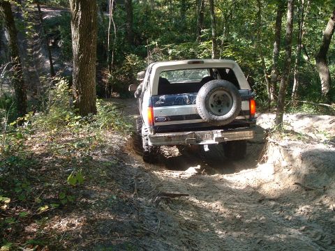 1995 Ford Bronco - This 1995 Ford Bronco navigates a challenging dirt trail through a wooded area.