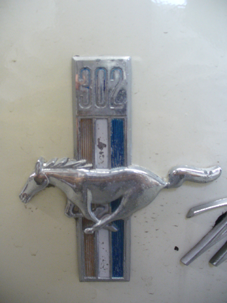1968 Ford Mustang - A close-up of a 1968 Ford Mustang emblem, the iconic running horse and a '302' badge.
