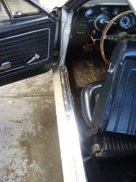 1968 Ford Mustang - The interior of a classic Ford Mustang shows its door panel, dashboard, and seating.