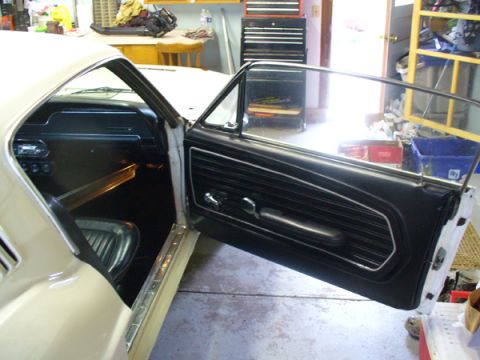 1968 Ford Mustang - The interior of a 1968 Ford Mustang shows its black door panel and tan exterior.