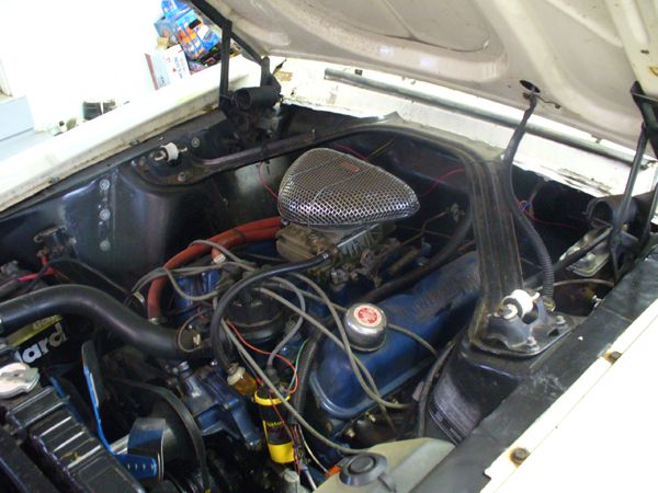 Engine bay with V8 engine, carburetor, and air cleaner. Some hoses and wires are visible