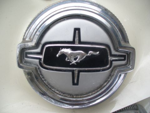 1968 Ford Mustang - Close-up of a 1968 Ford Mustang emblem, the iconic running horse logo on a chrome and black background.