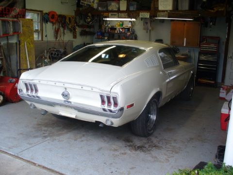1968 Ford Mustang - A white 1968 Ford Mustang is parked in a garage, showing its rear and side profile.