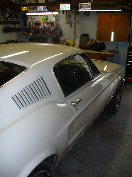 1968 Ford Mustang - White 1968 Ford Mustang coupe in a garage, viewed from the rear quarter panel.