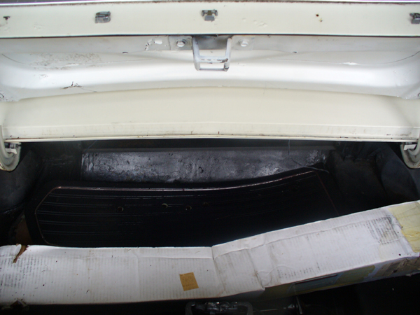 White car trunk interior with black mat and cardboard box