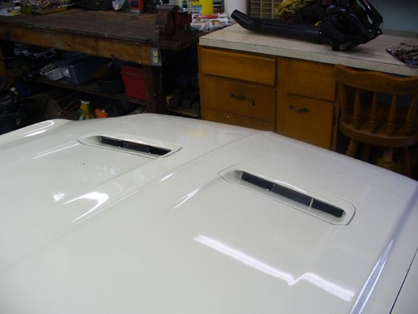 White hood with twin scoops and chrome turn signal indicator lenses in garage