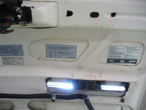 1968 Ford Mustang - Close-up of underhood labels and a light fixture, with some rust visible.