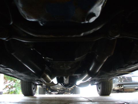 1968 Ford Mustang - The underside of a vehicle reveals a dual exhaust system and drivetrain components, with another car in the background.