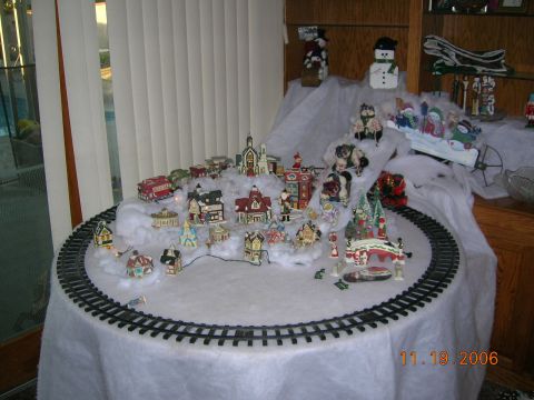 1985 Ford Bronco - A festive Christmas village scene is arranged on a table, complete with a miniature train track and decorative elements.