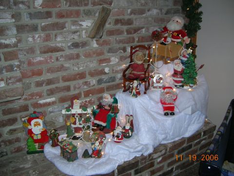 1985 Ford Bronco - A collection of Santa Claus figures and holiday decorations are arranged on a brick hearth.