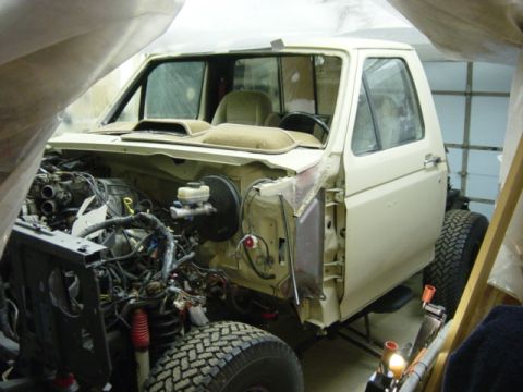 1991 Ford Bronco - This cream-colored Ford truck is undergoing chassis reassembly, with its engine compartment exposed.