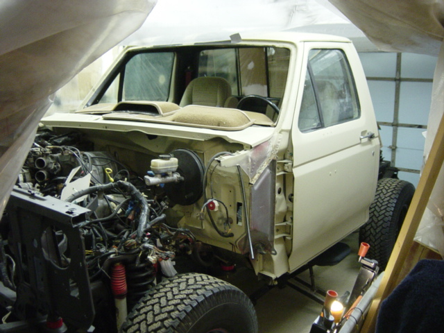 Cream-colored Ford truck with engine removed, viewed from the front-right