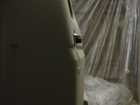 1991 Ford Bronco - Close-up of a vehicle's side panel and door handle, with plastic sheeting visible in the background.