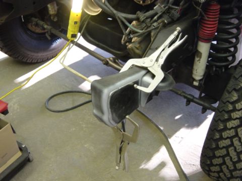 1991 Ford Bronco - Mechanic working on vehicle frame, using clamps to hold a part in place during repair.