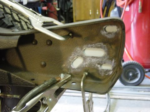 1991 Ford Bronco - Close-up of a vehicle frame section undergoing repair work, with welding clamps and grinding marks visible.