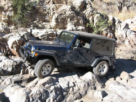 2005 Jeep YJ - A dark blue 2005 Jeep Wrangler TJ Rubicon navigates a rocky trail.