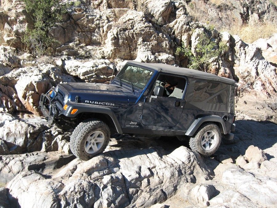 Dark blue Jeep Wrangler TJ Rubicon off-roading over rocks
