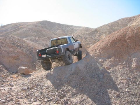 1997 Ford Ranger - A modified pickup truck navigates a steep, rocky incline in a desert landscape.