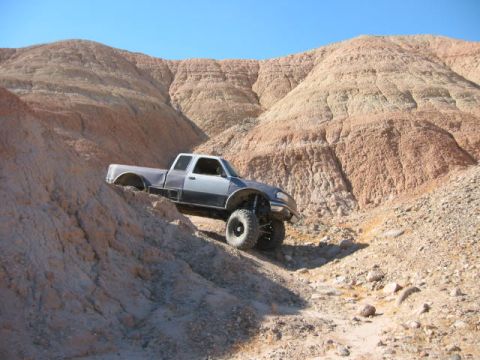 1997 Ford Ranger - A modified pickup truck navigates a challenging off-road terrain under a clear blue sky.