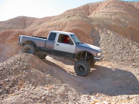 1997 Ford Ranger - This modified pickup truck is navigating a steep, rocky incline in a desert landscape.