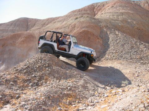 1997 Ford Ranger - A silver Jeep Wrangler navigates a steep, rocky incline under a clear sky.