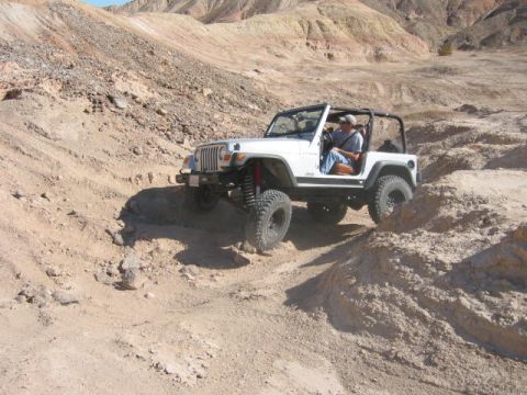 1997 Ford Ranger - A white Jeep Wrangler tackles a challenging off-road course in a desert landscape.
