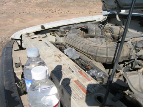1997 Ford Ranger - The engine bay of a white 1997 Ford Ranger is visible, with two water bottles placed on the fender.