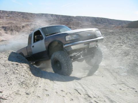 1997 Ford Ranger - A modified Ford Ranger navigates a rocky, dusty terrain with one wheel high in the air.
