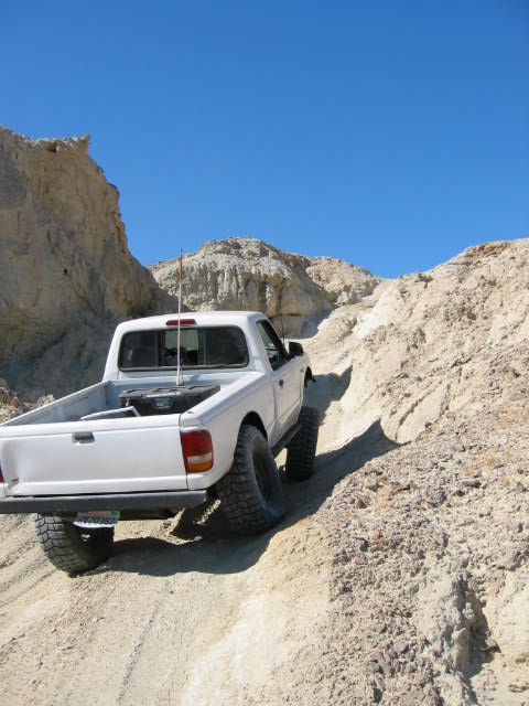 1997 Ford Ranger - A white 1997 Ford Ranger navigates a steep, sandy off-road trail under a clear blue sky.