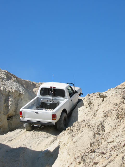 1997 Ford Ranger - A white 1997 Ford Ranger navigates a steep, sandy off-road trail under a clear blue sky.