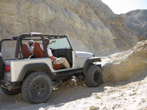 1997 Ford Ranger - A silver Jeep Wrangler navigates a rocky off-road trail in a desert canyon.