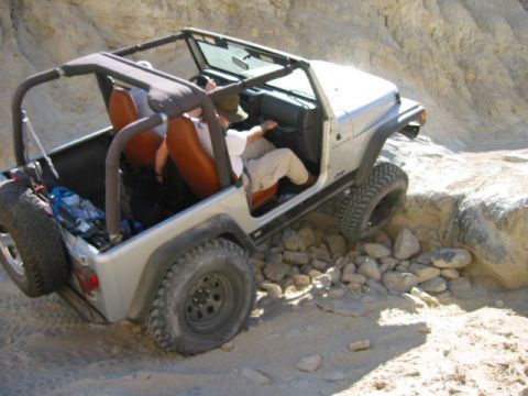 1997 Ford Ranger - Silver Jeep Wrangler tackling a challenging off-road trail with rocky obstacles.