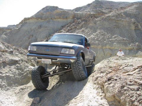 1997 Ford Ranger - A modified 1997 Ford Ranger navigates a steep, rocky off-road trail in a desert landscape.