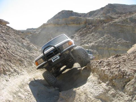 1997 Ford Ranger - A white 1997 Ford Ranger tackles a challenging rocky incline on an off-road adventure, with another vehicle visible in the background.