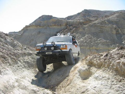 1997 Ford Ranger - Off-road SUV tackles a challenging rocky trail under a clear sky.