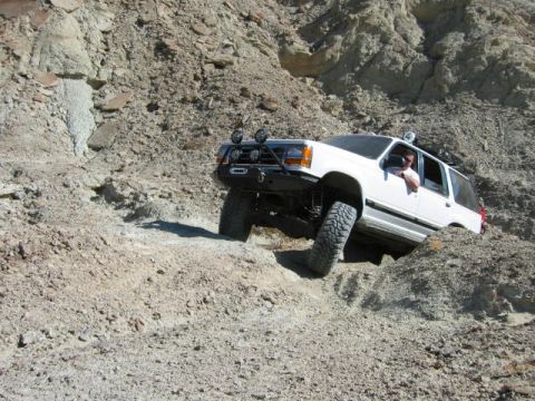 1997 Ford Ranger - This white SUV is navigating a steep, rocky incline with its front wheels high off the ground.