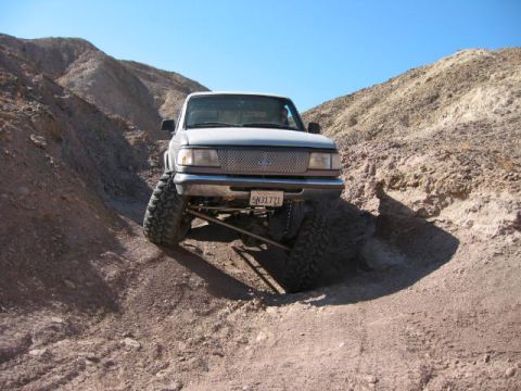 1997 Ford Ranger - A modified Ford Ranger navigates a steep, rocky incline under a clear blue sky.
