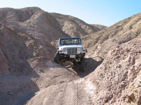 1997 Ford Ranger - A white Jeep Wrangler navigates a steep, rocky canyon off-road.