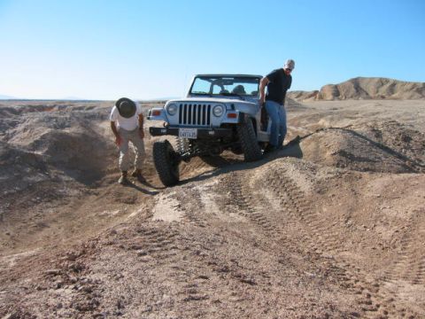 1997 Ford Ranger - A Jeep Wrangler navigates a challenging off-road terrain with two individuals observing its progress.