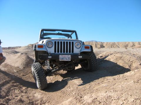 1997 Ford Ranger - A silver Jeep Wrangler navigates a desert trail under a clear blue sky.