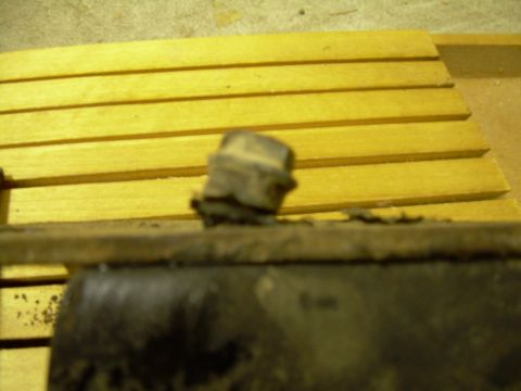 1978 Ford Bronco - A close-up view of a worn motor mount part, with yellow wooden slats visible in the background.