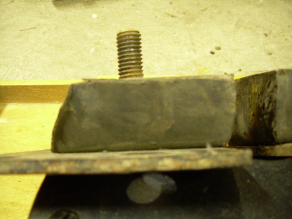 Close-up of a rusty metal motor mount with a rubber isolator and a threaded bolt
