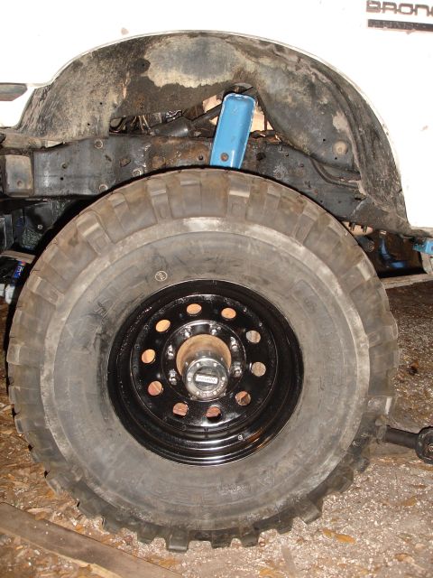 1989 Ford Bronco - Close-up of the wheel well and suspension of a 1989 Ford Bronco, revealing significant rust and a blue shock absorber.
