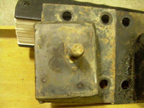 1978 Ford Bronco - A close-up view of a corroded motor mount, with a stack of papers partially visible.