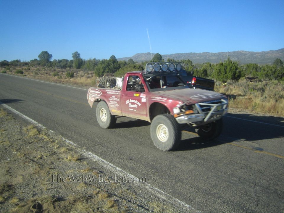 Dark red single-cab prerunner race truck on a desert highway