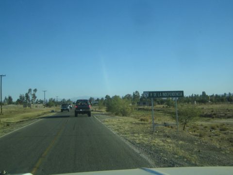 1990 Ford Bronco - rural paved road with a roadside sign reading H DE LA INDEPENDENCIA, with a dark pickup and other vehicles traveling ahead.