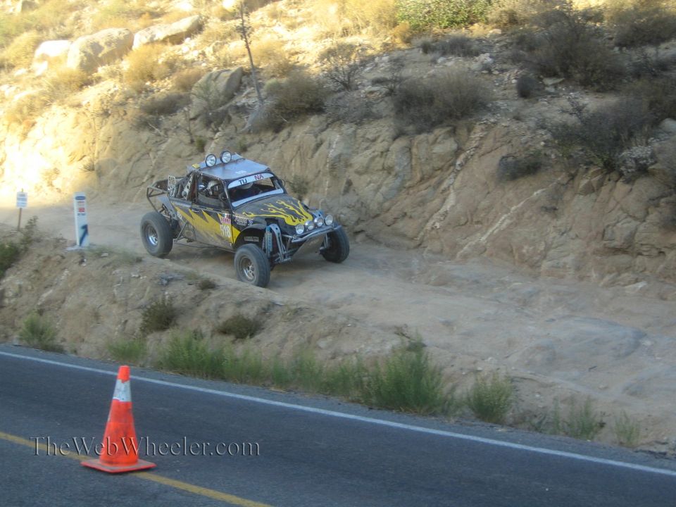 Black off-road race buggy with yellow flames on a dirt trail above a road
