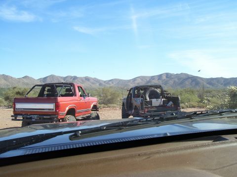 1991 Ford Bronco - Two SUVs are parked in a desert landscape with mountains in the background.